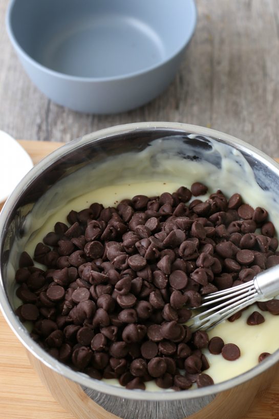 Chocolate chips being added to the homemade chocolate pudding mixture.